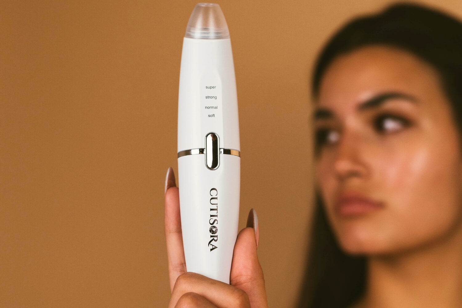 Жена, която държи устройството LED Вакуум за премахване на черни точки - Derma Clear пред себе си.